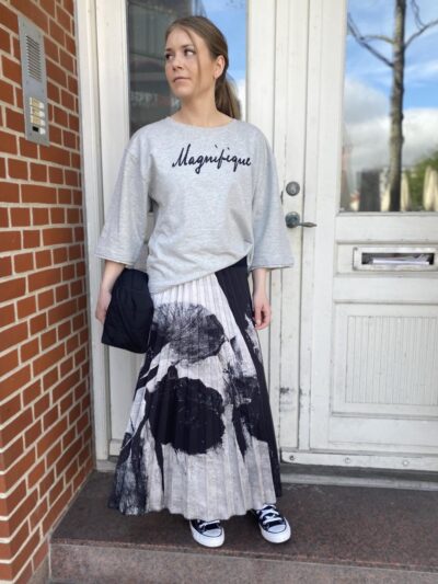 Marie i grå t-shirt og mønstret sort hvid nederdel