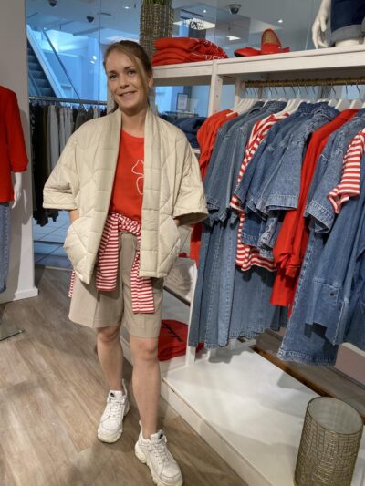 marie med rød t-shirt, beige vest og shorts