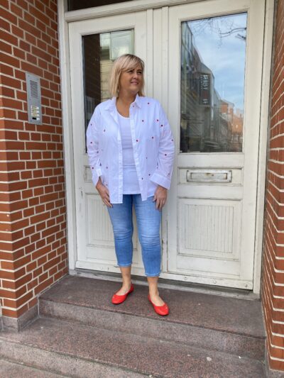janni med jeans og åben hvid skjorte med små røde hjerter på.ONLY Carmakoma CARNEW LINA GRACE SHIRT Bright White