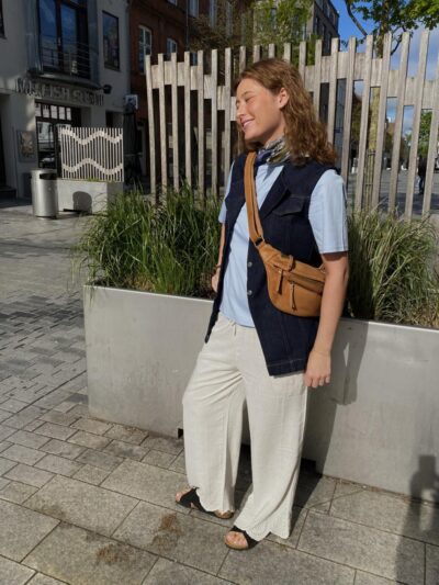 Marie med denimvest over blå t-shirt til beige bukser