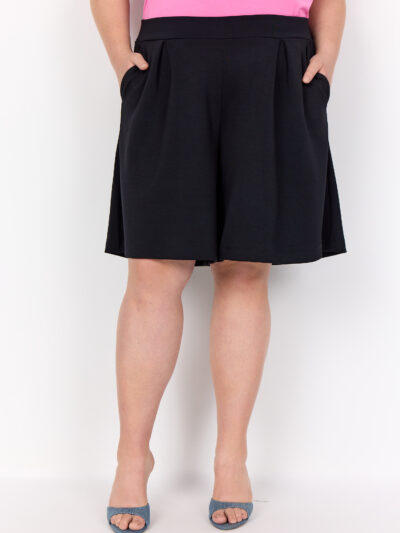model med hænderne i lommerne på sorte shorts i en afslappet pasform med lommer. Wasabi WA-SABINA 41 Shorts Black