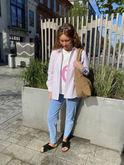 Luna i lyserød stribet skjorte åben over en t-shirt til et par jeans