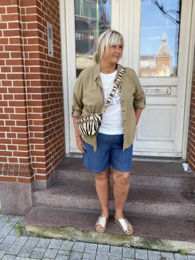 janni med åben grøn hørskjorte, hvid t-shirt og denimshorts