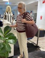 lene med en taske shopper og en stribet t-shirt og lyse bukser