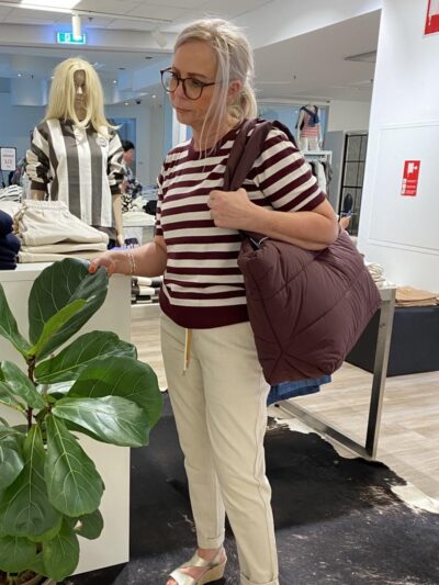 lene med en taske shopper og en stribet t-shirt og lyse bukser