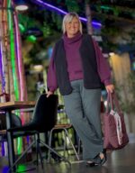 Janni med sort teddy vest over lilla striktrøje til et par grå bukser