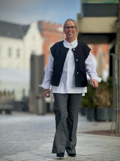 Lene med hvid skjorte, sort vest og grå bukser
