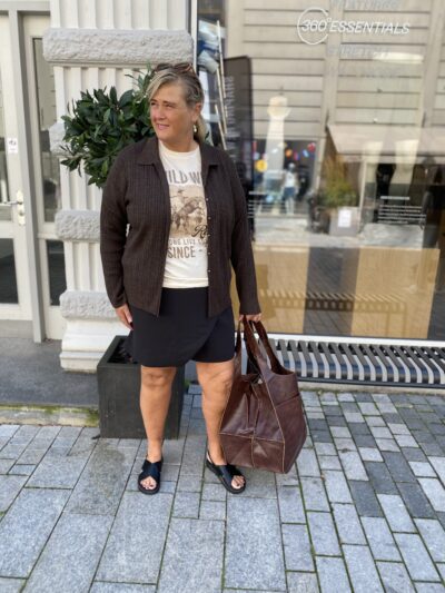 janni med sorte skorts, t-shirt og en brun kort cardigan