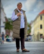 Janni med hvid skjorte og lang grøn vest med lynlås