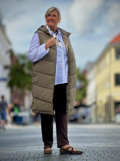 Janni med hvid skjorte og lang grøn vest med lynlås