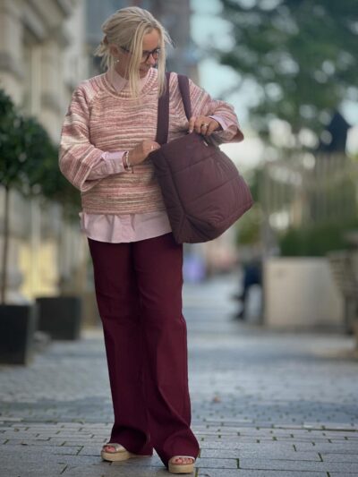 lene med lyserød skjorte, strik samt røde bukser og taske