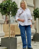 Janni med blå jeans og oversize hvid skjorte med skrift